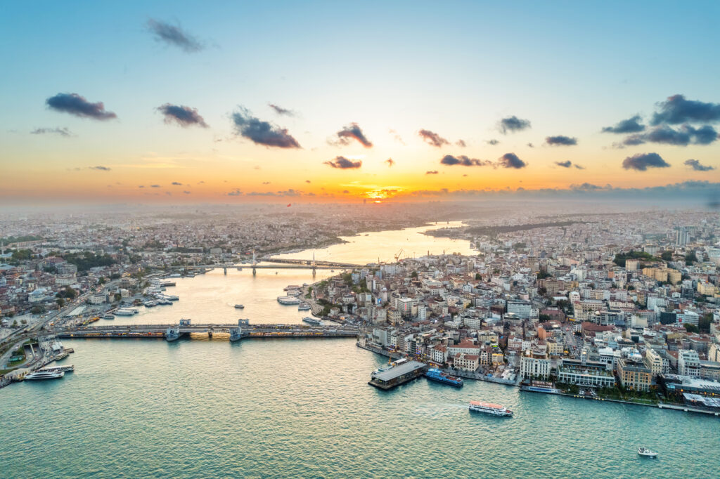 Aerial drone view of Istanbul at sunset, Turkey. Multiple residential buildings, mosques, Galata and Metro bridges over the Golden Horn waterway with floating ships